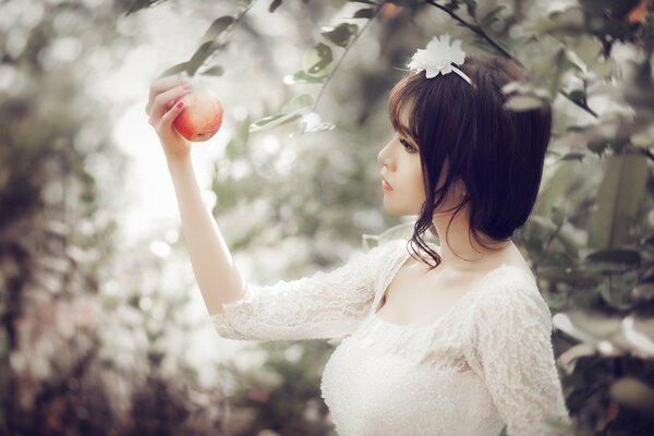 La jeune fille regarde une pomme rouge