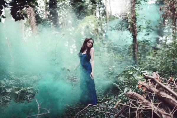 Chica en un vestido de lujo se perdió el ambiente de humo en el bosque