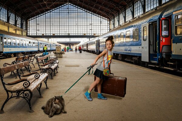 A girl with a cat on a leash on the platform in front of the train