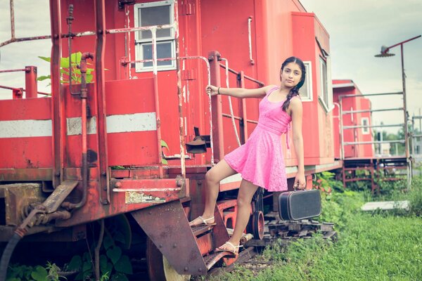 La jeune fille avec une petite mallette monte dans un vieux wagon