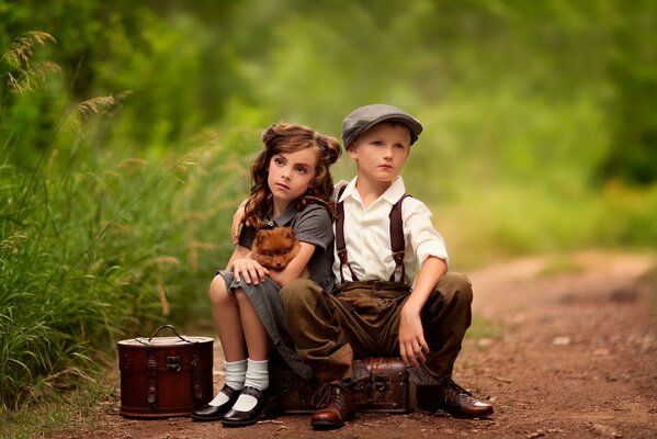 A boy and a girl are sitting on suitcases