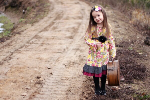 A little girl in a beautiful outfit and with a suitcase