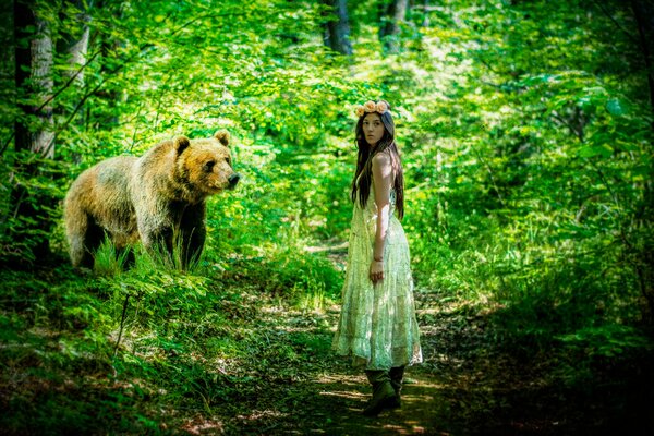 A girl in a dress in the forest with a bear