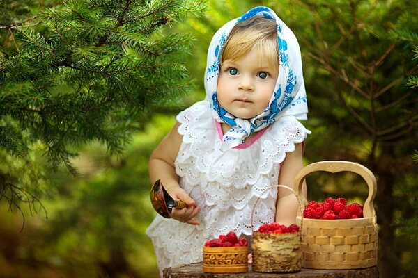 A girl in a handkerchief collects raspberries