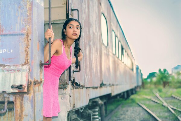 Du regard la jeune fille dans une robe rose. La jeune fille dans le train