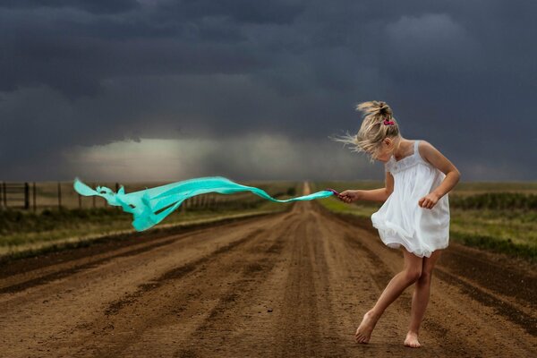 Una niña camina por el camino en una tormenta