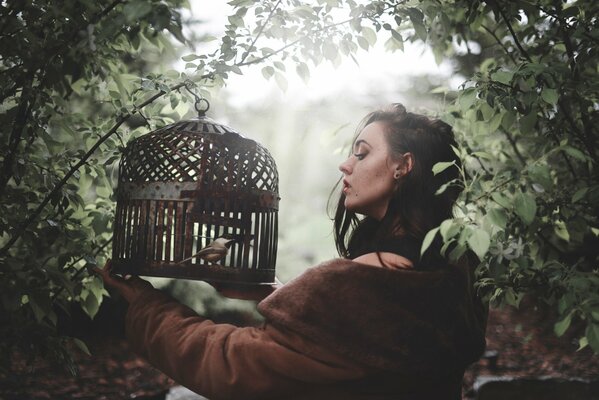 A bird in a cage and a girl about to let it out