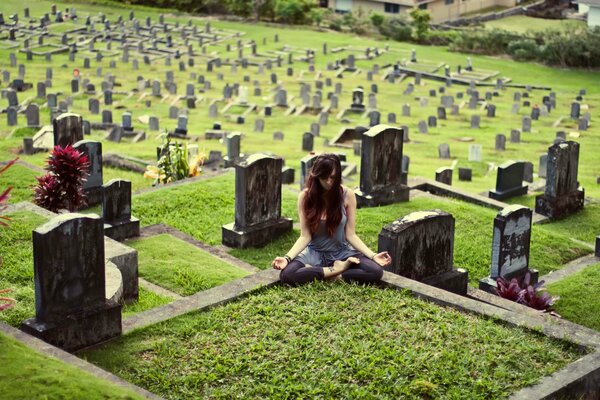 Mädchen in Lotus-Pose auf einem grünen Friedhof