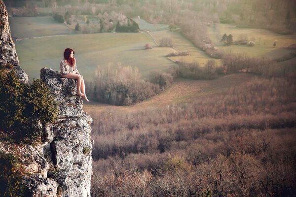 Redhead ragazza si siede su una roccia