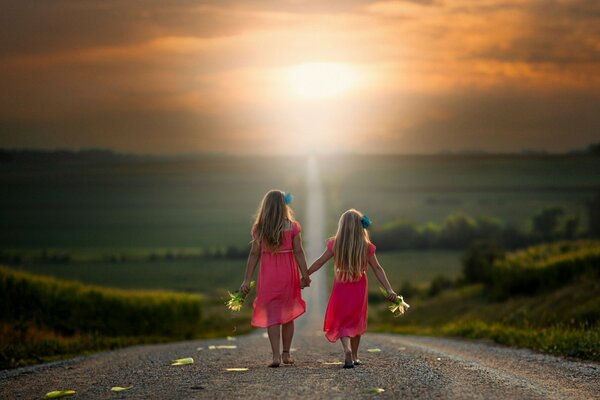 Two girls walk hand in hand along the road