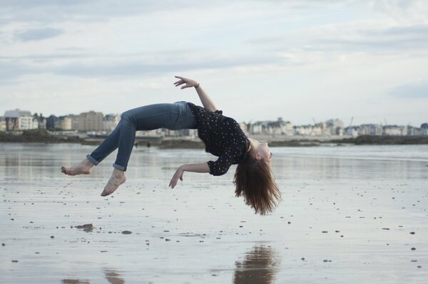 Chica en la playa en la ciudad, levitando