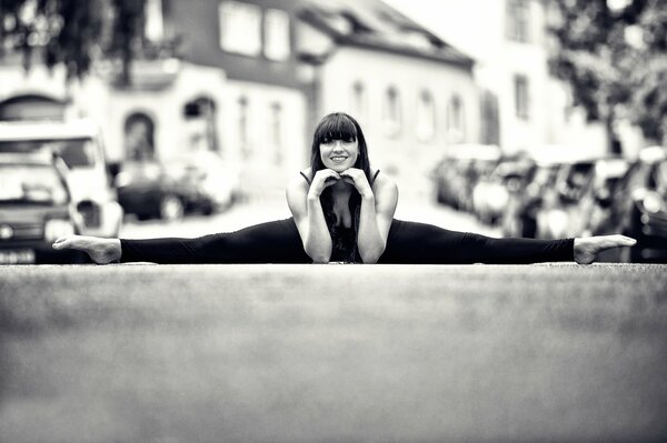 The girl sat down on the splits on the street