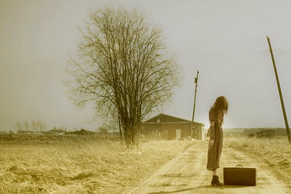 Chica en el fondo de un campo con una maleta