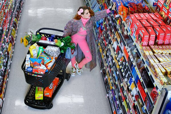 Chica en los estantes de la tienda con un carrito