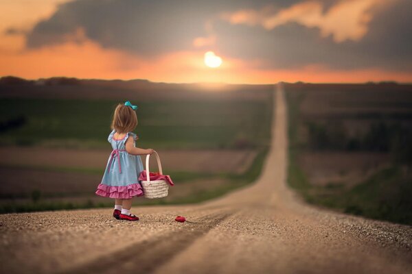 Fille sur le chemin du coucher du soleil avec panier