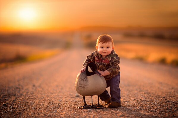 Sunny road with a boy hugging a bird