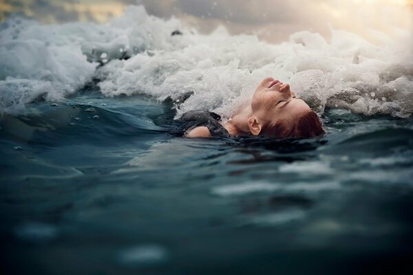 La jeune fille couchée sur le dos dans les vagues