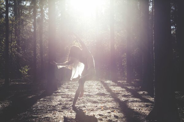 La jeune fille danse dans une robe blanche dans le soleil mari