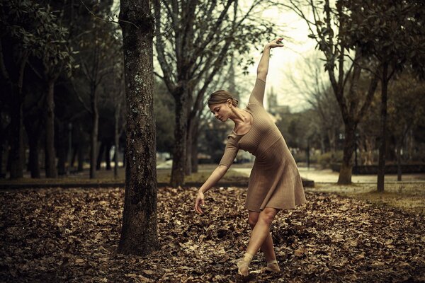 Ragazza che balla sul fogliame autunnale