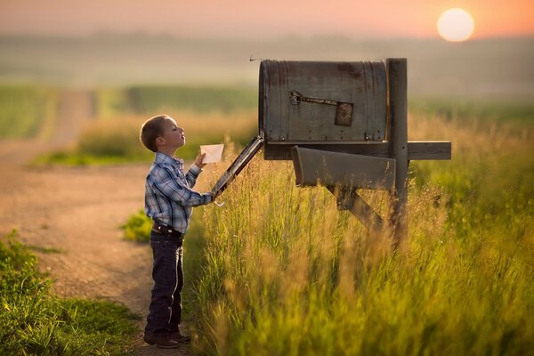 Junge schaut in einen großen alten Briefkasten