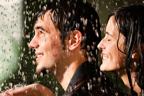 Chico y chica sonriendo bajo la lluvia