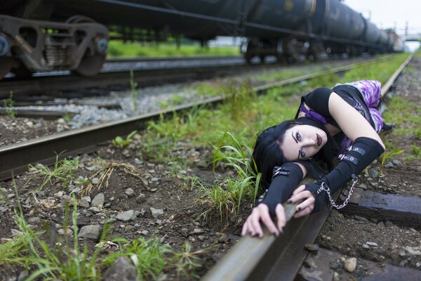 A girl is lying on a railway rail