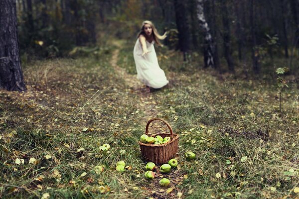 La jeune fille court vers le panier avec les pommes