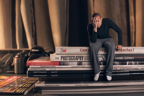 El chico se sienta en libros y revistas