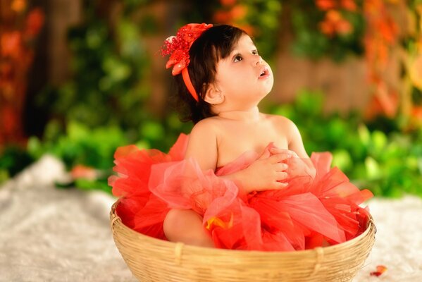 A little girl in a red outfit is sitting in a karzin