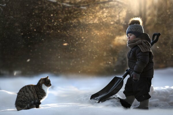 Ein Kind mit einer Katze kam heraus, um den Schnee zu entfernen