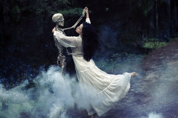 A girl in a long dress dances with a skeleton