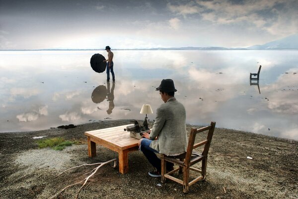 A man is sitting at a table on the river bank