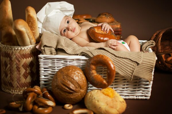 Niño cansado cocinero en una cesta de pan