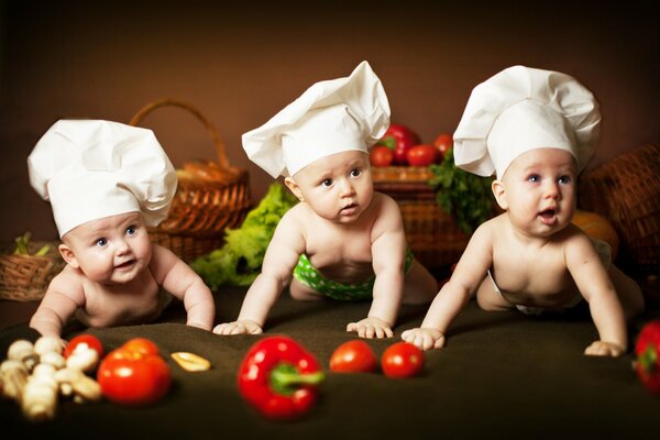 Piccoli bambini in cappelli da cuoco tra verdure e cestini