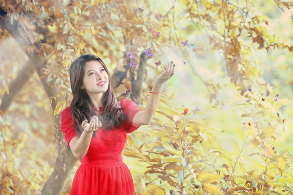 Asian woman in red admires butterflies