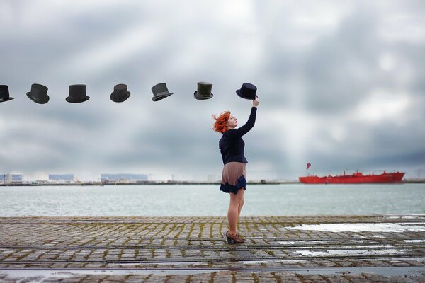 Chica con sombreros en el muelle