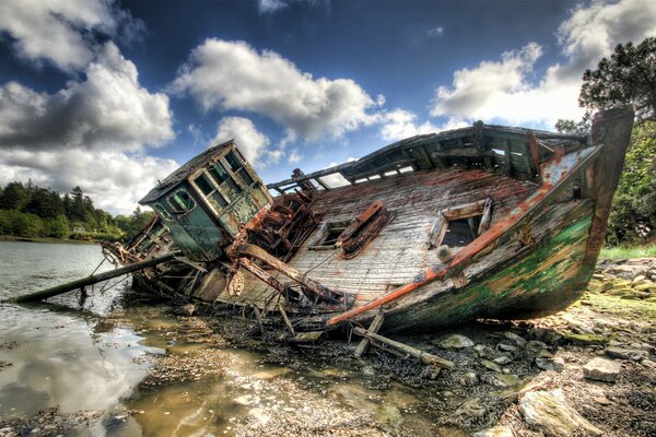 Viejo barco destruido en la orilla del río