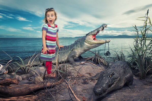 A little girl depicts fright standing among alligators on the bank of a river