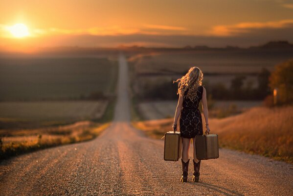 A lady with suitcases is walking along the road