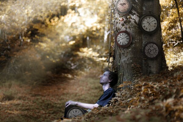 Im Wald sitzt ein Mann mit einer Uhr am Baum