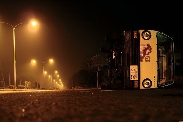 The bus is lying on its side on the road