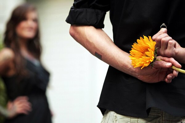 Ein Mann mit einer Blume und einem Ring macht einem Mädchen ein Angebot