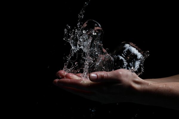 Hand mit Spritzwasser auf schwarzem Hintergrund