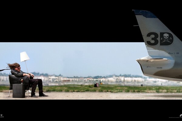 A man is sitting on a chair in front of the plane