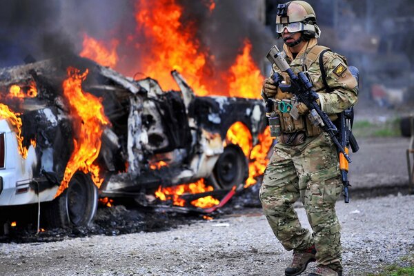 Soldat en pleine tenue n fond de voiture en feu