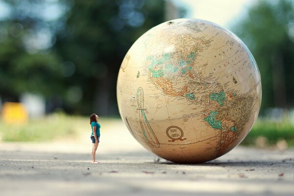 The girl looks at the big globe