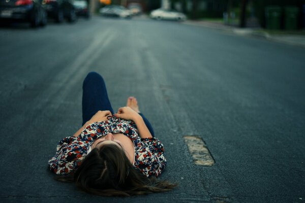 The girl is lying on the asphalt