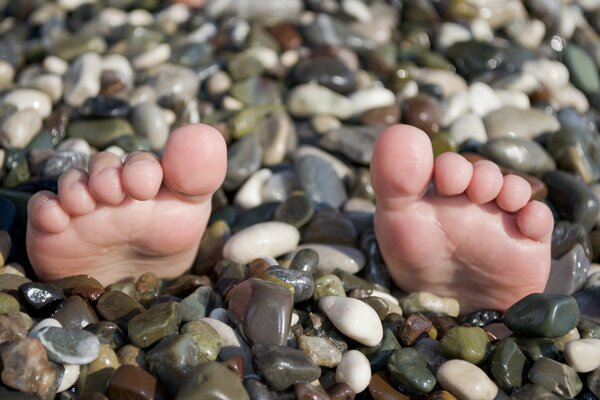 Los pies enterrados en guijarros sobresalen solo los dedos de los pies