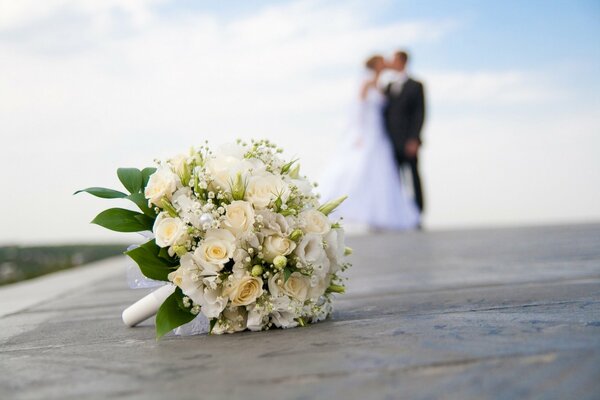 Wedding bouquet in close-up and the bride and groom in the background