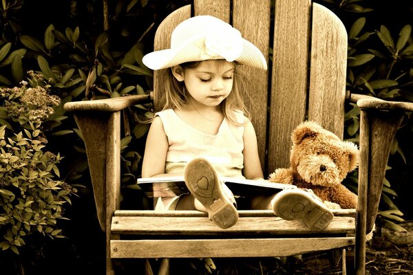 A little girl will sit on a chair with a book m bear